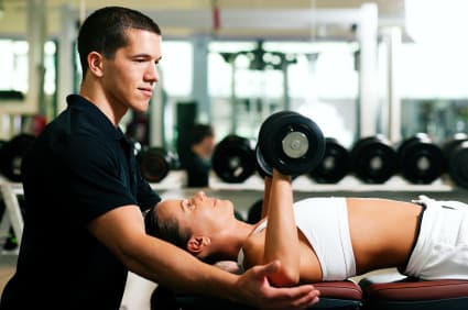 A personal trainer spots a client during a chest press